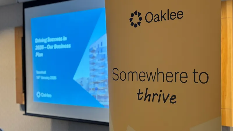 A close-up of an Oaklee branded banner beside a presentation screen displaying the Town Hall business plan title slide.